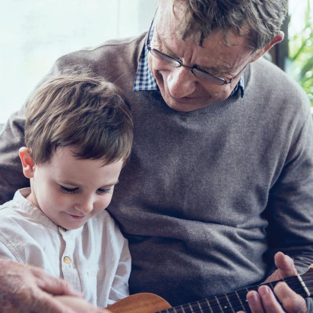 Grandfather teaching grandson how to play the guitar