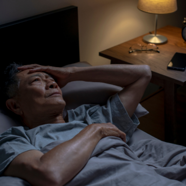 Man laying in bed having trouble sleeping