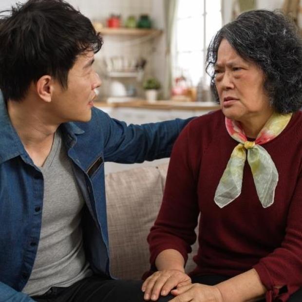 Mother with pained expression sitting on couch with her son