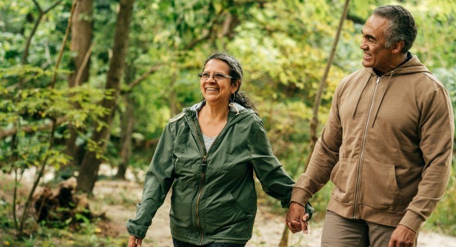 Hispanic couple walking in the woods holding hands