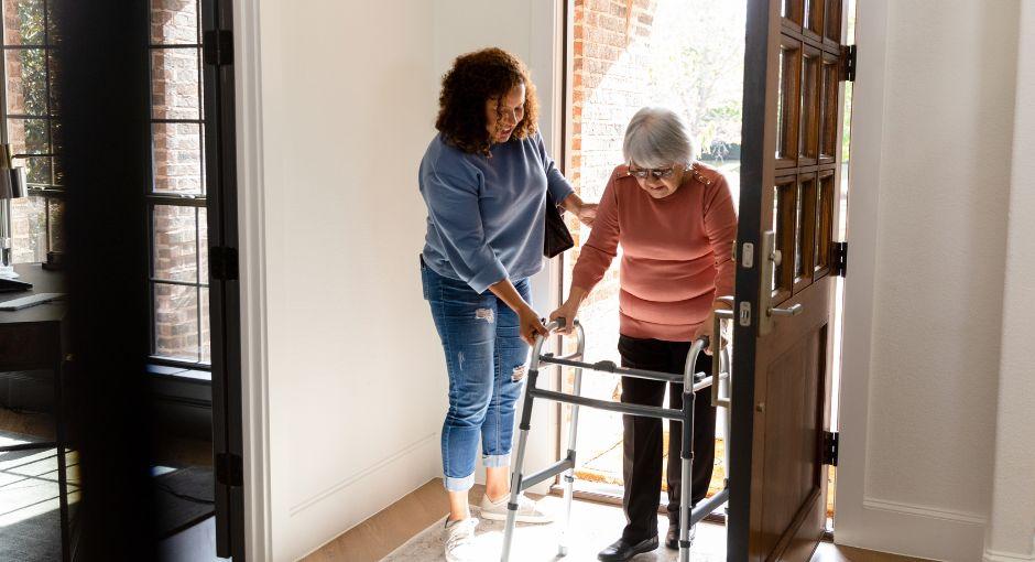 Caregiver assisting an elderly woman with a walker