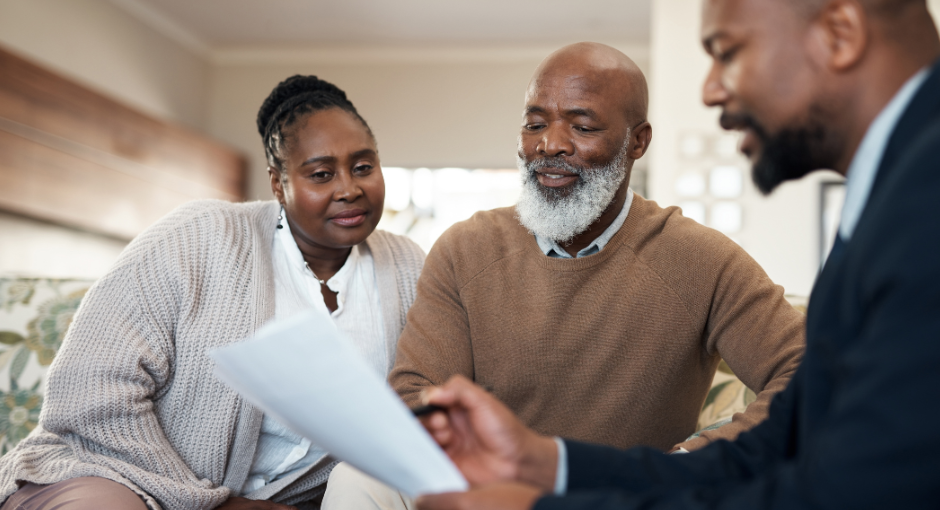 An older African American couple consults a paper held by a financial advisor