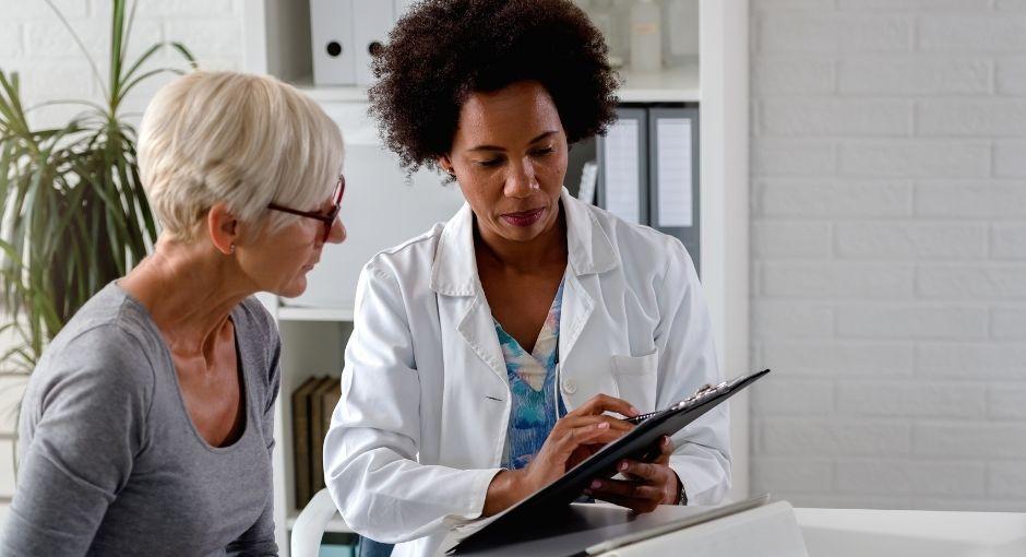 Female doctor and female patient sitting together looking at paperwork