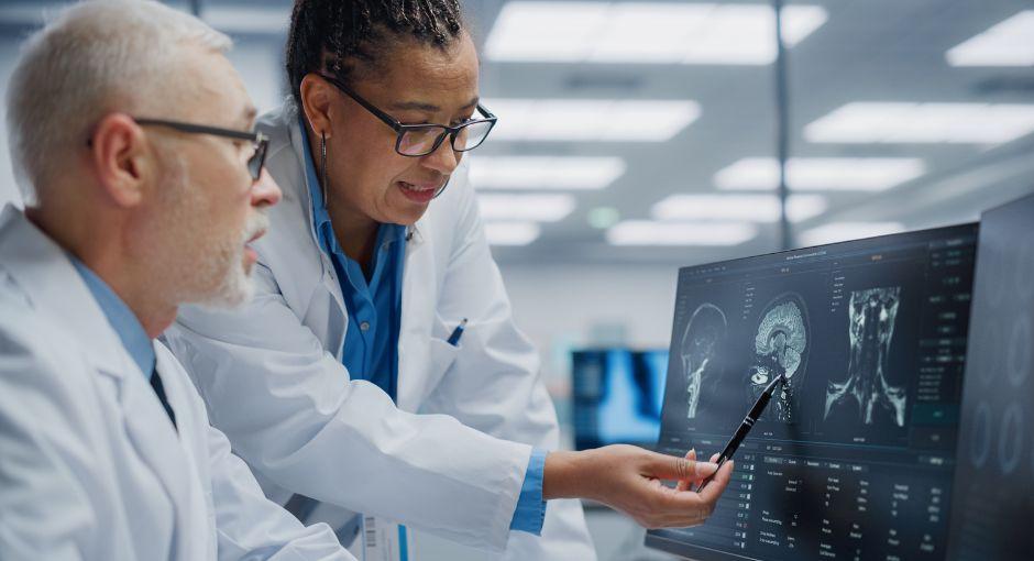 Two neurologist reviewing brain scans on a screen