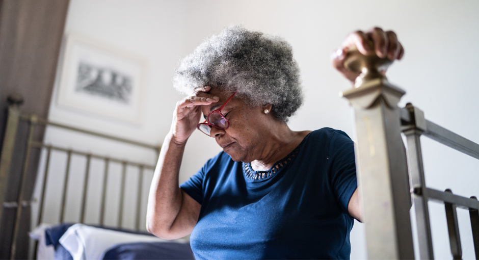 Woman sitting on bed holding head because she's feeling dizzy