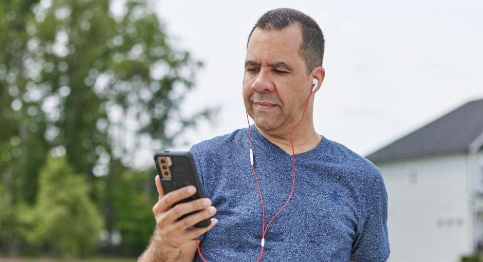 Man on a walk looking at his phone with headphones on