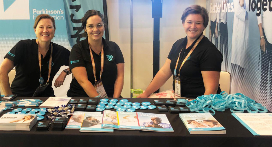 Three Parkinson's Foundation employees smiling at the Parkinson's Foundation booth at a past World Parkinson's Congress