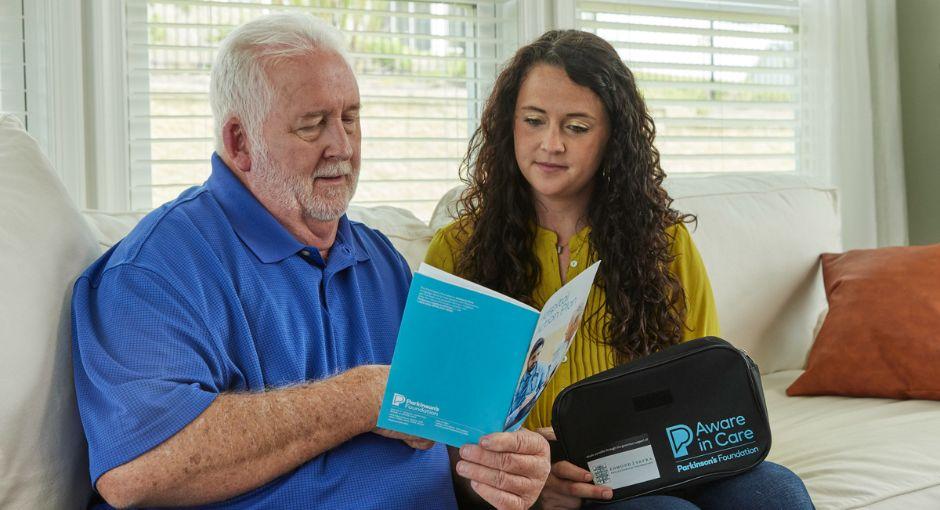 Man sitting on the couch with his daughter looking at a pamphlet from the kit