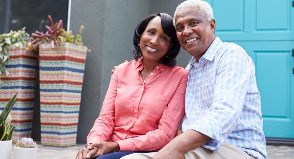 Black husband and wife sitting next to each other on their porch