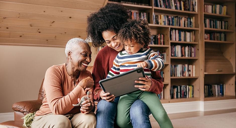 Multigenerational African American family sits watching virtual programming on a tablet