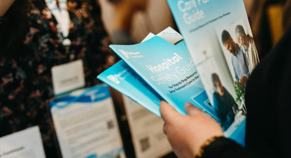 Person holding multiple Parkinson's Foundation resource booklets