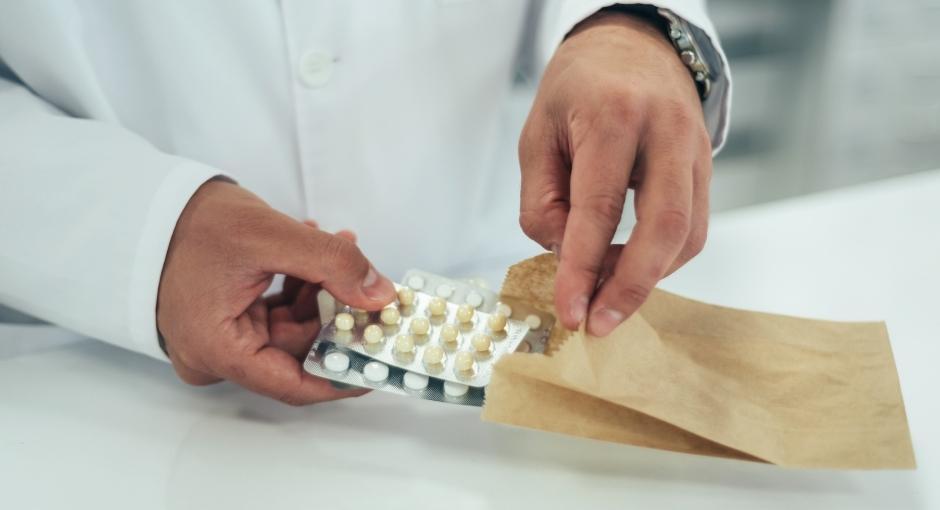 Closeup shot of pharmacists putting medicine in a bag