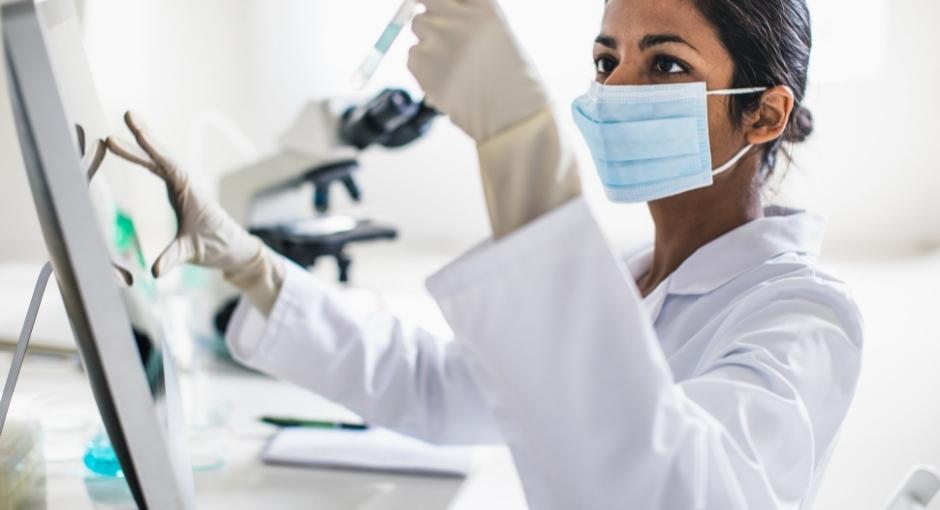 Researcher in lab looking at vial