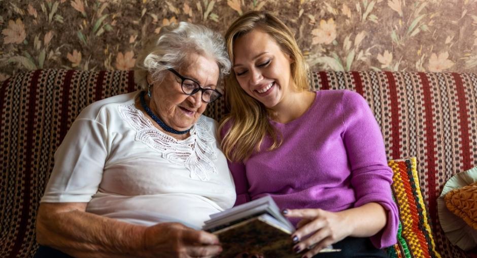 Woman and adult daughter sitting on couch with book