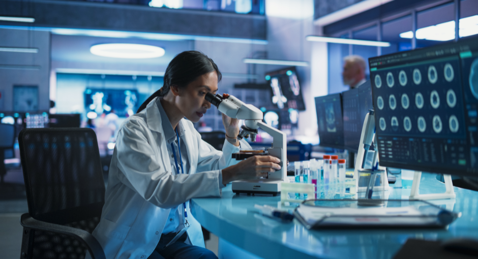 female scientist viewing a slide under a microscope in lab setting