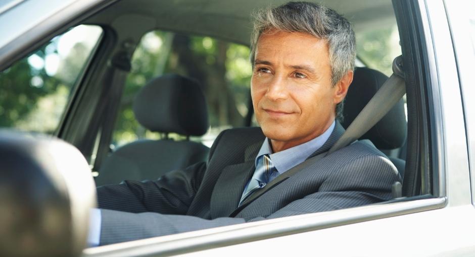 Smiling man in a suit driving a car