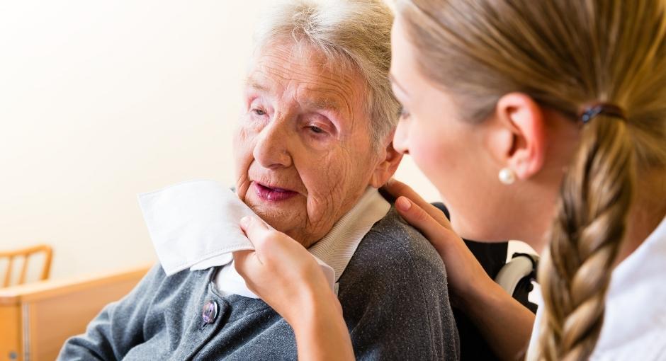 Daughter using napkin to wipe drool from her mom's face