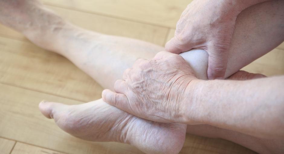 Person with bare legs grabbing one of their ankles with both hands