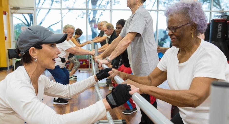 Parkinson's exercise class with instructor and student stretching at a barre