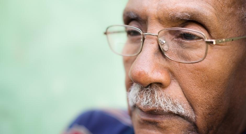 Close-up of man wearing glasses staring into distance with serious expression
