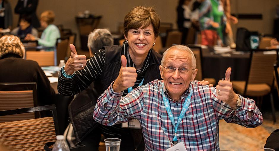 Excited man and woman giving thumbs up gesture at educational event