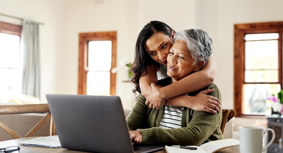 Two family members hugging in front of a laptop screen