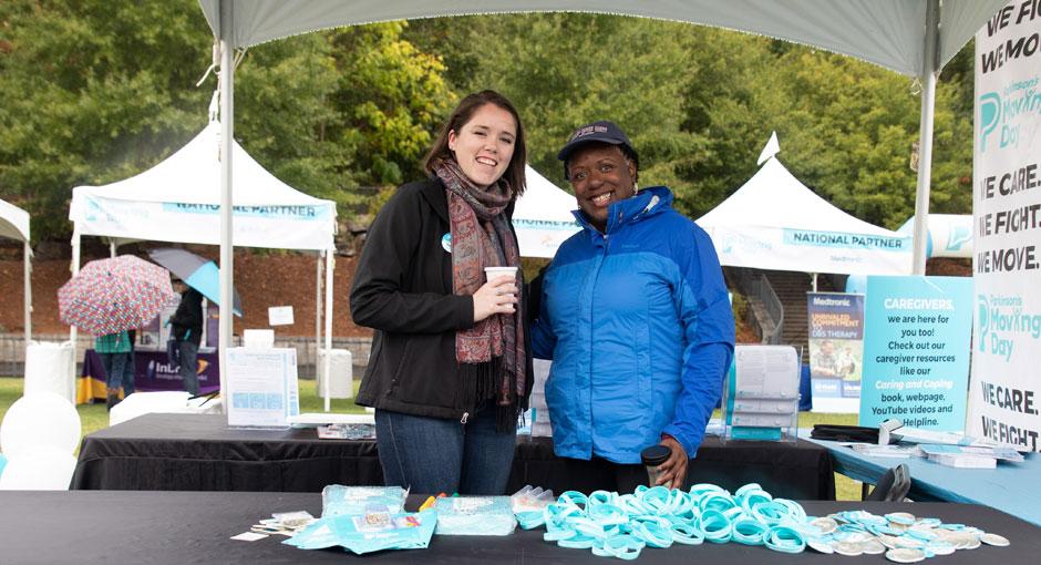 Two people at an event booth smiling