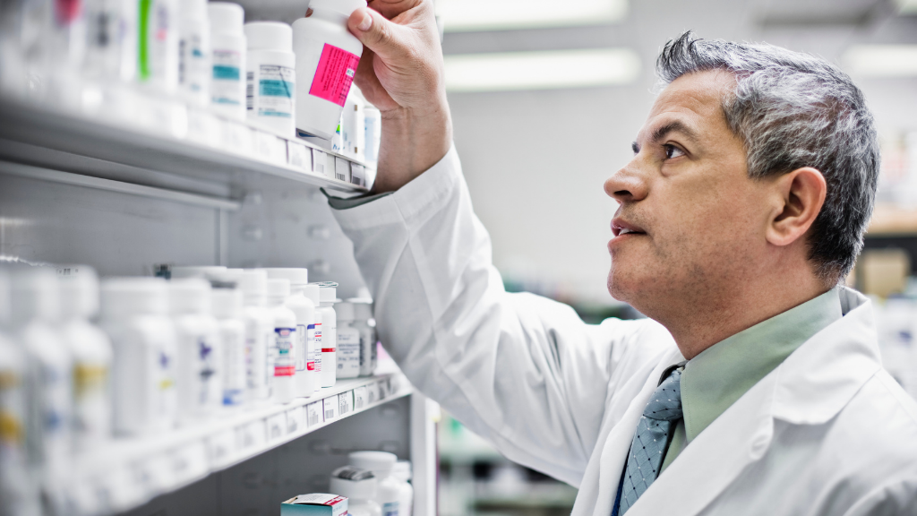 Pharmacist organizing pill bottles on a pharmacy shelf