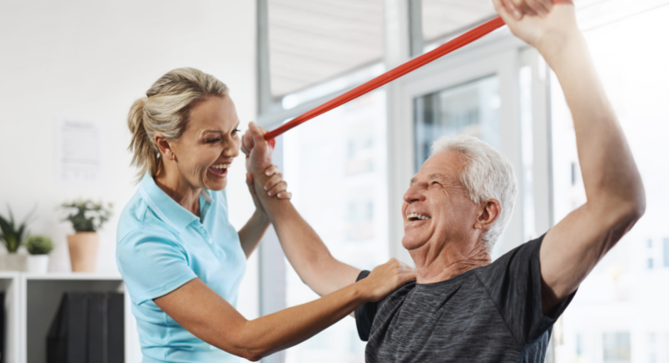 Man using resistance band above head while physical therapists assists
