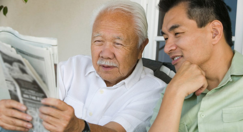 Grandfather and son reading a newspaper together