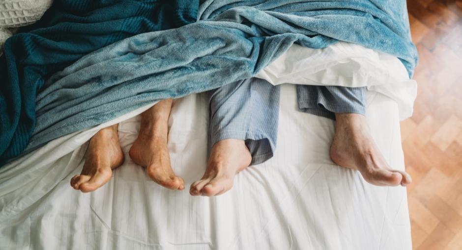 Two pairs of feet peeking out under blanket