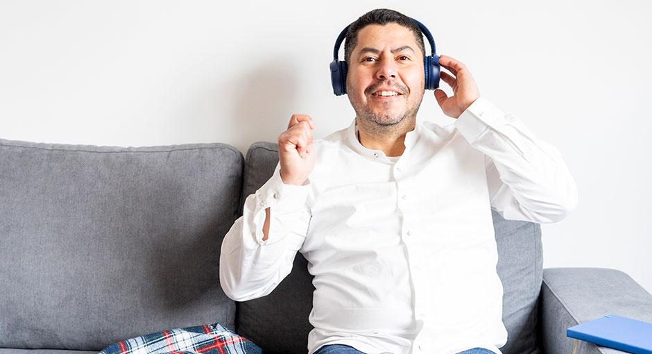 Latino man on the couch wearing headphone and enjoying music