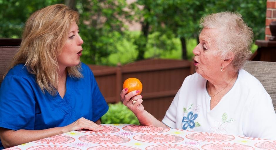 Speech therapist working with patient holding up an orange