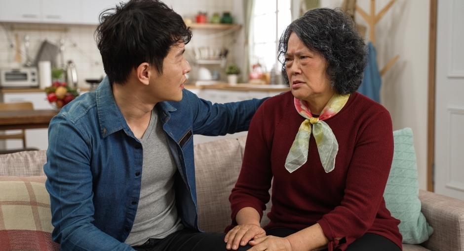 Mother with pained expression sitting on couch with her son