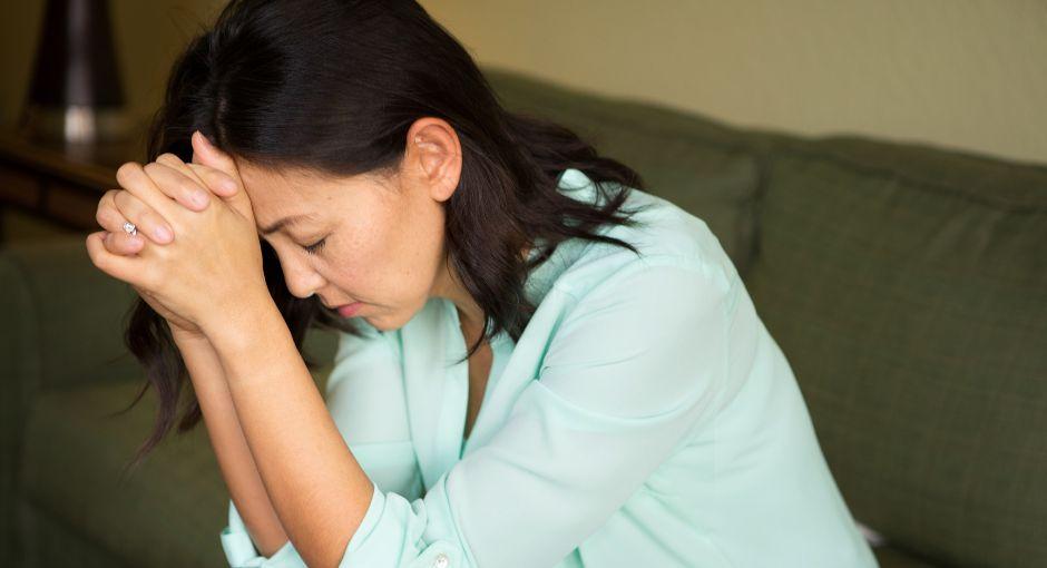 Woman with her head in her hands while experiencing dizziness