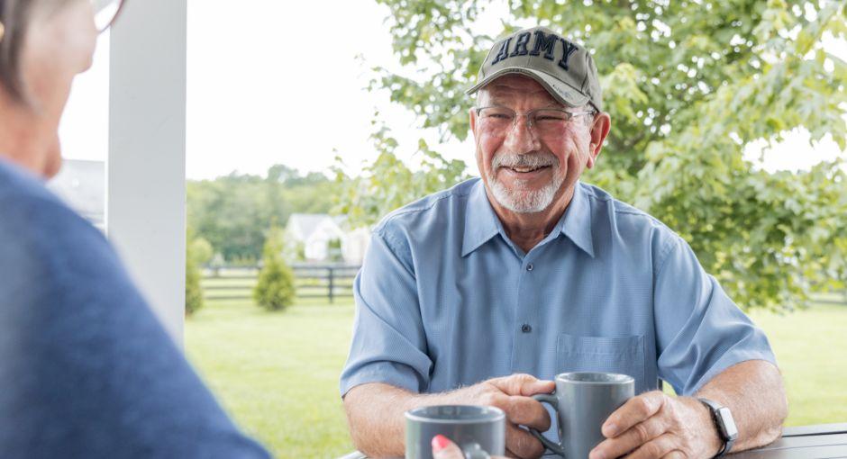 Army veteran sitting outside with a woman while drinking coffee.